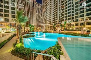 a large swimming pool with palm trees and buildings at EcoVinhomes Grand Park in Long Bình