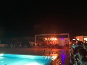 a group of people standing around a swimming pool at night at Cala Rosa Club Hotel in Stintino