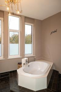a large white tub in a bathroom with windows at 135qm Loft vor den Toren Hamburgs in Schenefeld