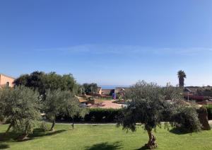 a group of trees in a park with the ocean in the background at Cala Rosa Club Hotel in Stintino