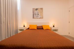Un dormitorio con una cama grande con dos almohadas naranjas. en VIP Baía Beach, en Machico
