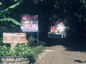 a sign in front of a road with a house at Koslanda Rest & Homestay in Koslanda