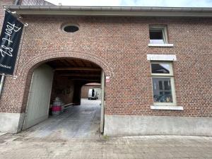 a brick building with an archway and a window at Maison Quatre-Vingt-Deux in Maasmechelen