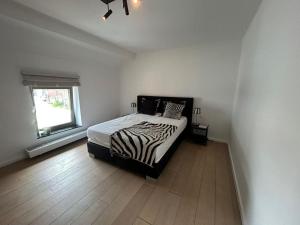 a zebra print bed in a white room with a window at Maison Quatre-Vingt-Deux in Maasmechelen