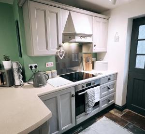 a kitchen with white cabinets and a stove top oven at Mynydd A Môr in Trevor