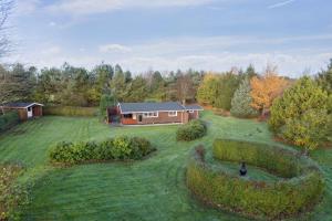 a house in the middle of a yard with hedges at Relaxing Holiday Home Near Water And Jesperhus in Roslev