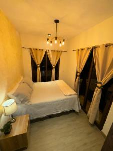 San Pedro Las HuertasにあるCasa Completa Boutique #3 cerca de Antigua Guatemalaのベッドルーム1室(カーテン付きの大型ベッド1台付)