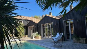 una casa con piscina e sedia bianca su una terrazza di Maison d architecte contemporaine la pierre blanche a Bordeaux