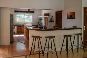 a kitchen with a bar with three stools at Villa Oasis in Nguékokh
