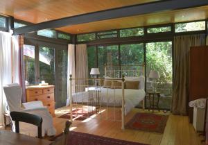 a bedroom with a bed in a room with windows at Glasshouse In The Winelands in Stellenbosch