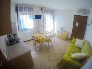 een keuken en een woonkamer met een tafel en een gele bank bij Residence Mediterraneo - Agenzia Cocal in Caorle