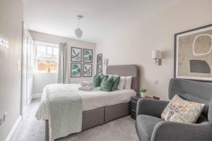 a bedroom with a large bed and a chair at Modern 2 Bed Oasis - Private parking & Garden in Windsor