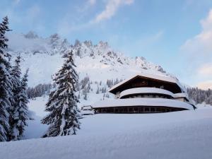 a building in the snow in front of a mountain at Berghotel Arthurhaus in Mühlbach am Hochkönig