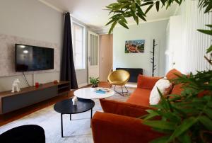 sala de estar con sofá naranja y TV en Petit Bengale, en Talence