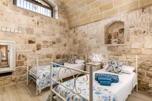 two beds in a room with a stone wall at Villa Amico by Villa Plus in Grottaglie