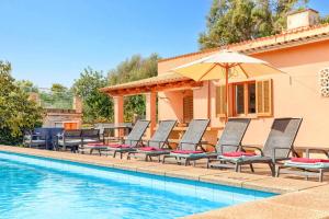 a group of chairs and an umbrella next to a swimming pool at Villa Andreu by Villa Plus in El Port
