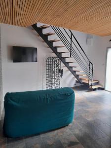 a living room with a staircase and a green couch at O coeur du medoc in Saint-Julien-Beychevelle