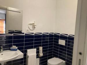 a blue tiled bathroom with a toilet and a sink at Cala Rosa Club Hotel in Stintino