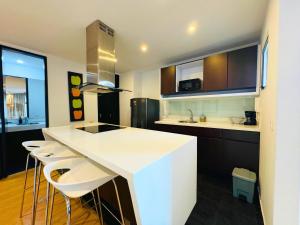 a kitchen with a white counter and some stools at Continental Aparthotel Bogotá - Aparta Suite in Bogotá