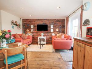 a living room with red furniture and a brick wall at The Bike Shed in Romsey