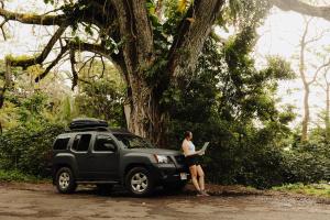 卡胡卢伊Budget Hack Maui SUV camping的一名女子站在一辆黑色卡车旁，手里拿着一台笔记本电脑