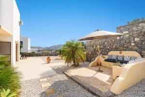 a patio with two chairs and an umbrella at Villa Petalouda by Villa Plus in Kalathos