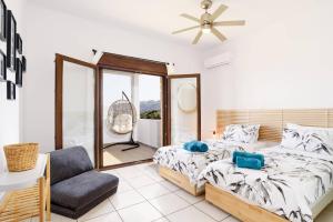 a bedroom with two beds and a fan and a chair at Villa Petalouda by Villa Plus in Kalathos +13 photos