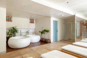 a large bathroom with two white tubs and plants at Brisas do Lago em Brasília in Brasilia