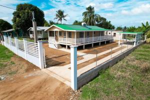 una casa con tetto verde e recinzione bianca di Elenas Modern 2BR Comfy Home a San Ignacio