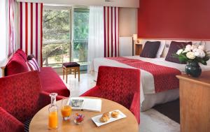 a hotel room with a bed and a table and chairs at The Originals Boutique, Hôtel Les Strélitzias in Juan-les-Pins