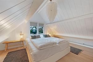 a white bedroom with a bed and a chandelier at Jonkerstee 217 - Ouddorp - NOT FOR COMPANIES in Ouddorp