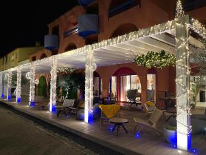 a white pergola with chairs and tables and lights at Cit'Hotel des 2 Golfs in Port Leucate
