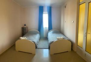 two beds in a small room with a window at Pronto in Kikinda