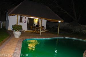 a swimming pool with a hut and a house at Bara Guesthouse in Welkom