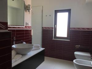 a bathroom with a sink and a toilet and a window at Cala Rosa Club Hotel in Stintino