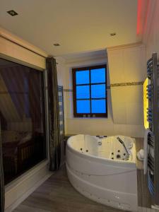 a bathroom with a large white tub and a window at Jaśminowy Dwór in Rokietnica +51 photos