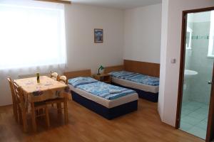 Zimmer mit 2 Betten, einem Tisch und einem Bad in der Unterkunft Penzion Semerád v Hevlíně in Hevlín