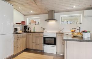 Una cocina con gabinetes de madera y un refrigerador blanco. en Holiday Home Løkken 7, en Løkken