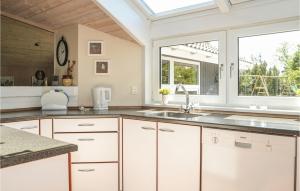 a kitchen with white cabinets and a window at Holiday Home Bøgelunden Oksbøl Ii in Oksbøl
