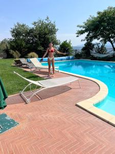 a woman in a bikini standing next to a swimming pool at Villa Alce in Fontanarosa +5 photos