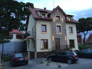 a house with two cars parked in front of it at Apartamenty Puk Puk in Mrągowo