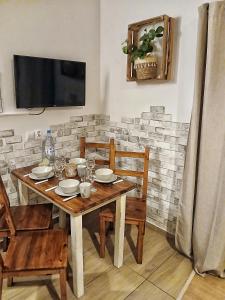 a wooden table with chairs and a television on a wall at Eleonor Accommodation exclusive house in Liszki