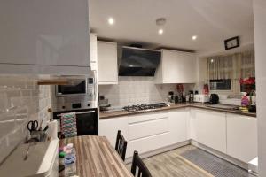 a kitchen with white cabinets and a wooden table at Lizola Homes Rooms in Dagenham