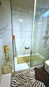 a shower with a glass door and a zebra rug at Lizola Homes Rooms in Dagenham