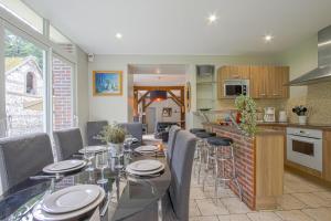 a kitchen and dining room with a glass table and chairs at Le Petit Château de Conteville in Paluel