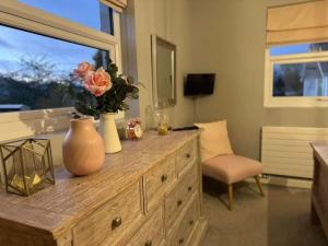 a vase with flowers on a dresser in a room at Bounty On The Lakes in Bowness-on-Windermere