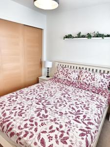 a bedroom with a bed with a red and white comforter at 4 miles to Westhill by Lains Lettings in Aberdeen