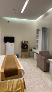 a bedroom with a bed and a couch and a tv at فندق قمم الصفوه الفندقيه in Rafha