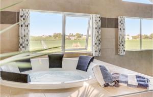 a room with a tub with two chairs and windows at Gorgeous Home In Stege With Sauna in Stege