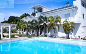 a swimming pool in front of a house with palm trees at Seascape Beach Resort Oslob in Oslob